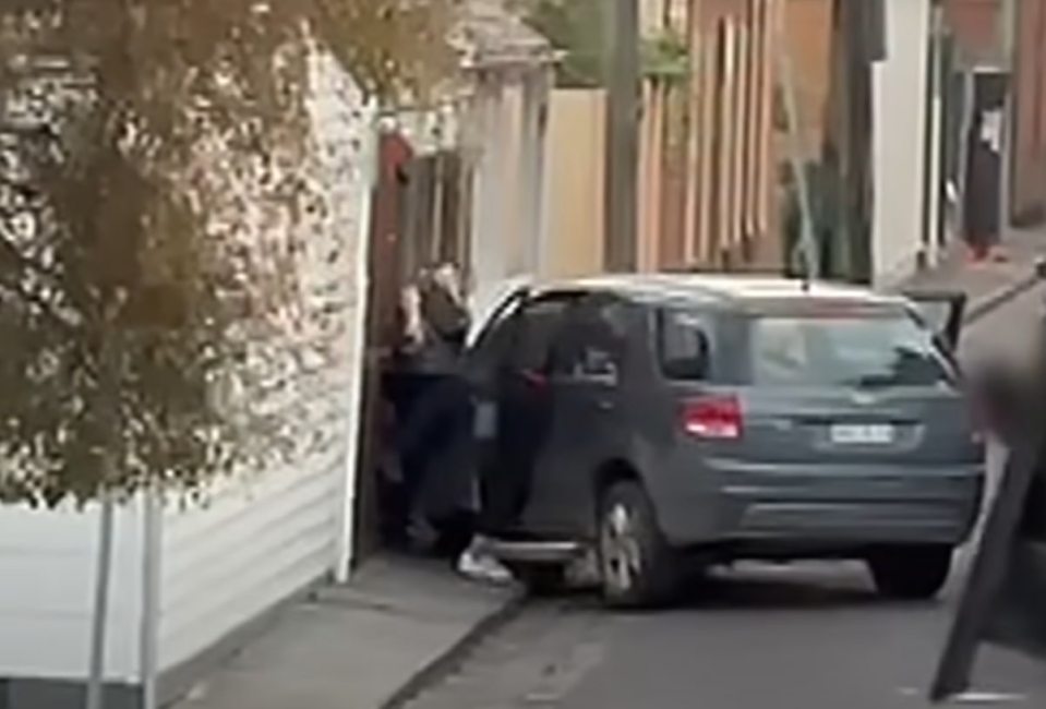 Un oficial de policía que detiene a una mujer al lado de un automóvil.