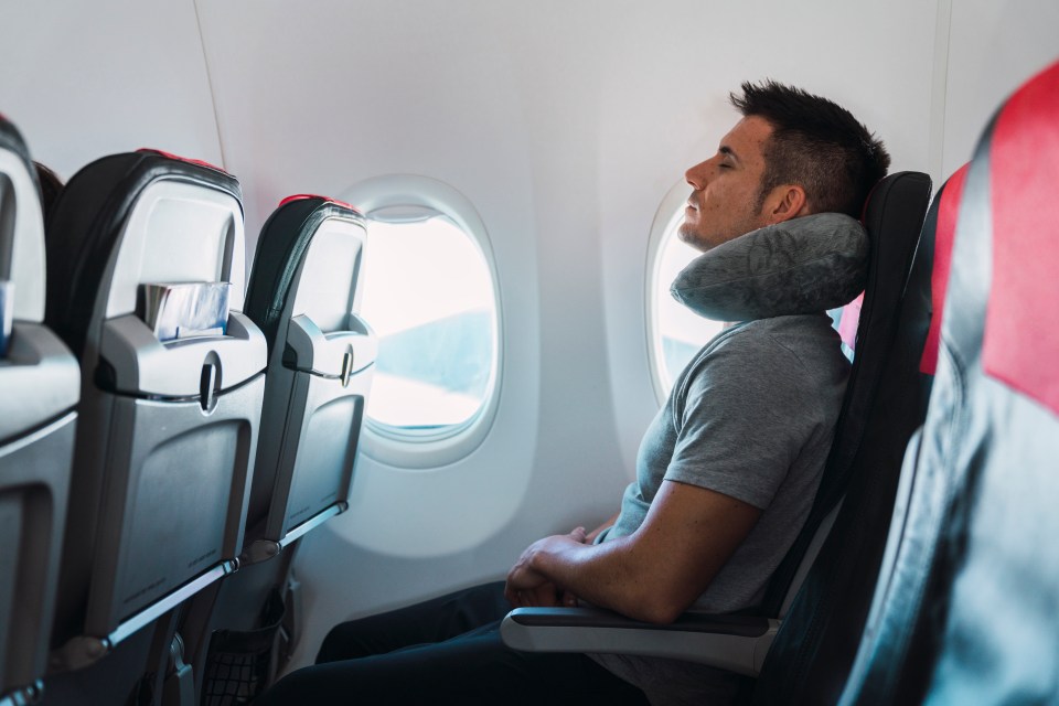 Hombre durmiendo en el avión con almohada del cuello.