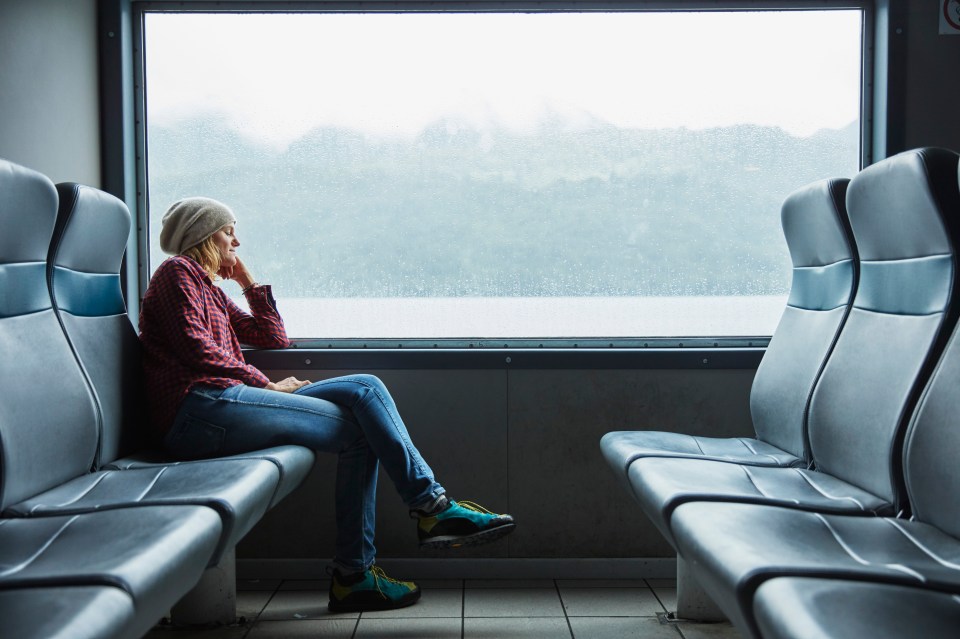 Mujer durmiendo en un ferry, mirando por la ventana.