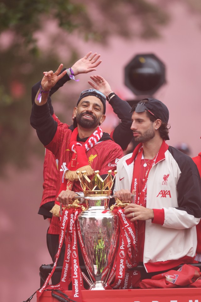 Mohamed Salah y otro jugador de Liverpool celebran con el trofeo de la Premier League en un autobús desfile.