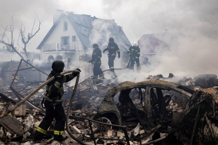 Trabajadores de emergencia que apagan un fuego en los escombros de una casa destruida en los ataques aéreos