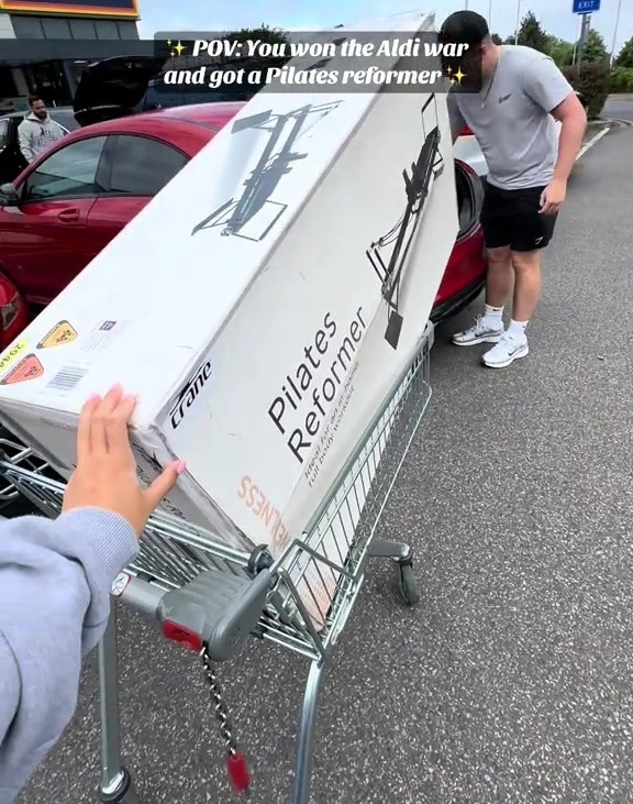 Persona que carga un reformador de Pilates en un carrito de compras fuera de una tienda Aldi.