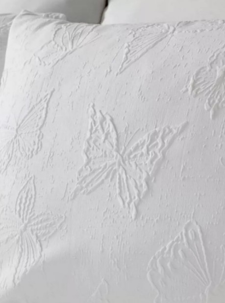 Funda de almohada blanca con patrón de mariposas en relieve.