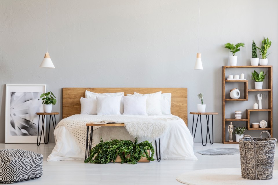 Dormitorio brillante con ropa de cama blanca, muebles de madera y plantas.