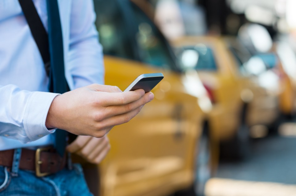 Primer plano de las manos de un hombre usando una aplicación para teléfonos inteligentes para llamar a un taxi.
