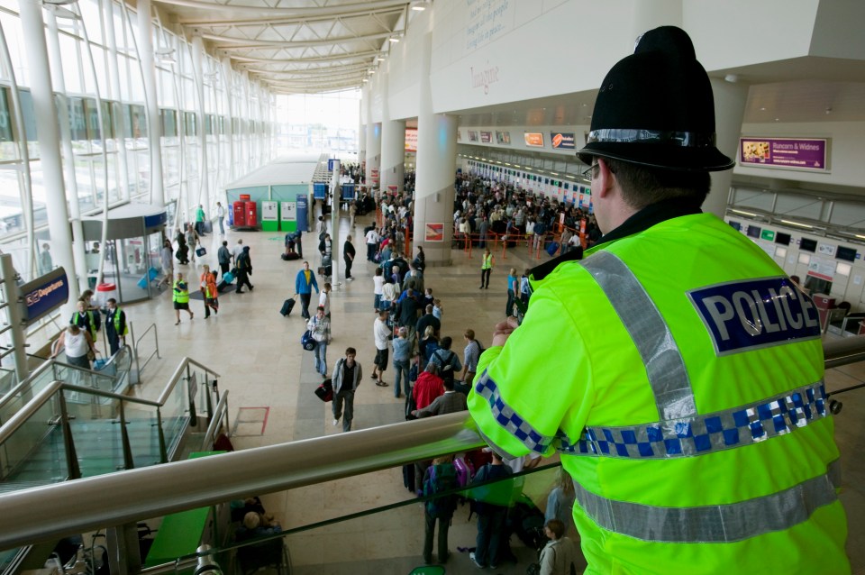Oficial de policía con vistas a los pasajeros del aeropuerto.