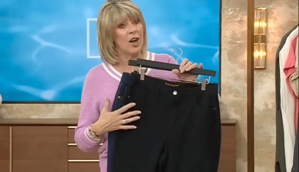 Ruth Langsford sosteniendo un par de pantalones negros en una percha.