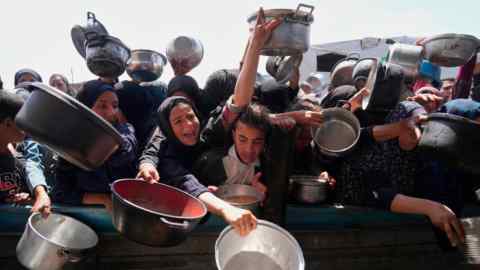 Los palestinos luchan por obtener comida donada en una cocina comunitaria en Khan Younis