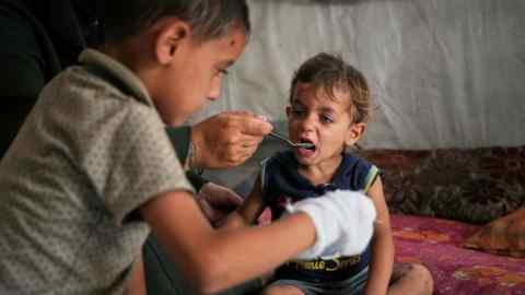 Un niño es alimentado por su madre con comida de una cocina comunitaria en el campamento de Muwasi para palestinos desplazados en Khan Younis, Southern Gaza Strip