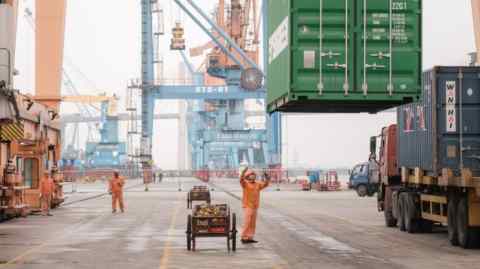 Un trabajador ayuda mientras se baja un contenedor en un puerto en Haiphong, Vietnam