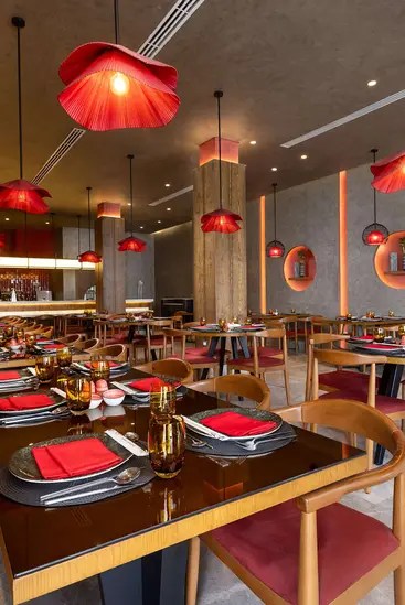 Interior de restaurantes con luces colgantes rojas y mesas para cenar.