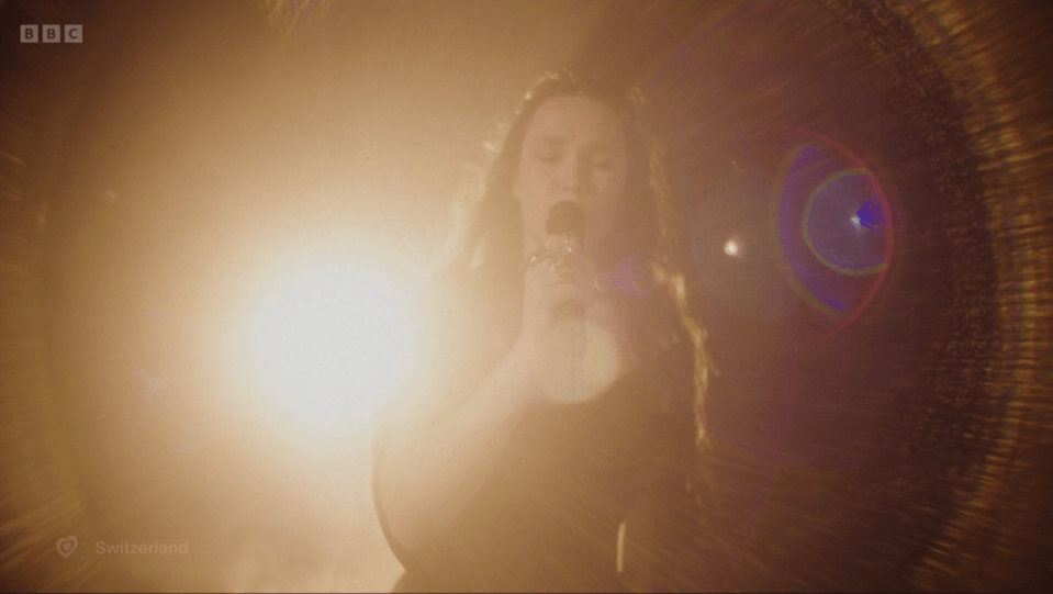 Captura de pantalla de una mujer cantando en un micrófono en el escenario.