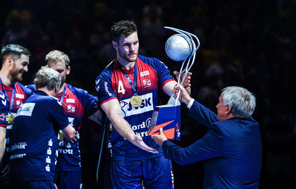 SG-Kapitän Johannes Golla (27) erhält von EHF-Präsident Michael Wiederer (69/r.) nach dem Titelgewinn 2024 den Pokal