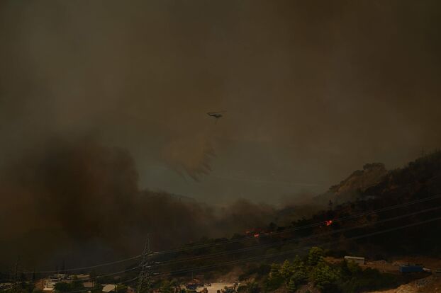 Un hélicoptère pulvérise de l'eau sur un incendie de forêt près de Patras.