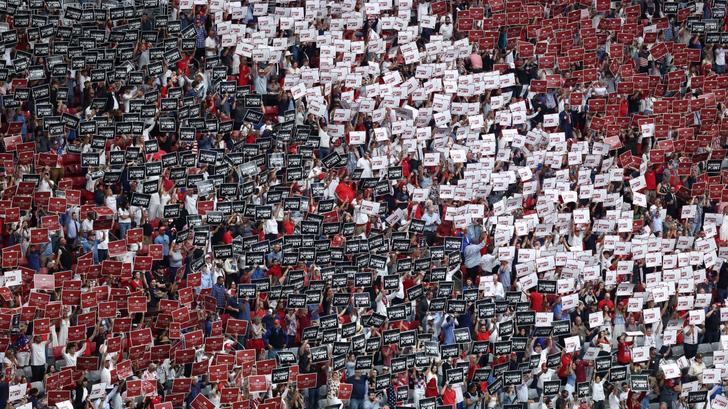 Les participants brandissent des pancartes avant la cérémonie commémorative publique en l’honneur de l’activiste d’extrême droite Charlie Kirk au State Farm Stadium de Glendale, en Arizona, le 21 septembre 2025.
