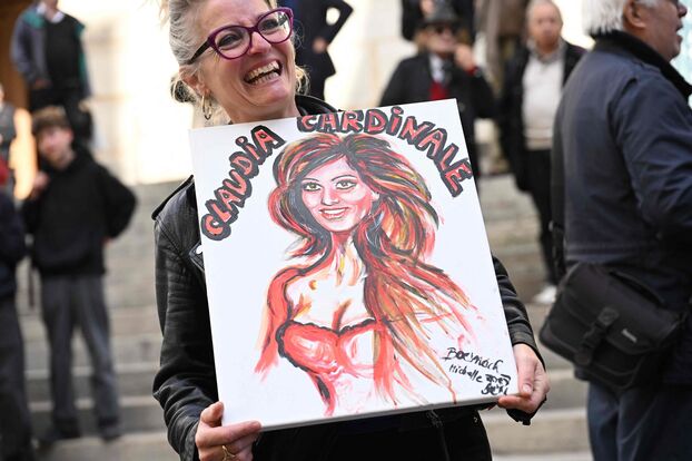 Une admiratrice de Claudia Cardinale tenant un portrait à son effigie aux abords de l'église Saint-Roch. AFP.