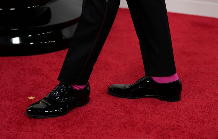 Ryan Gosling portait des chaussettes rose vif sous son costume noir.
