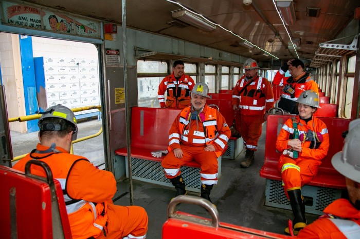 Sept personnes en tenue de sécurité minière sont assises dans le train