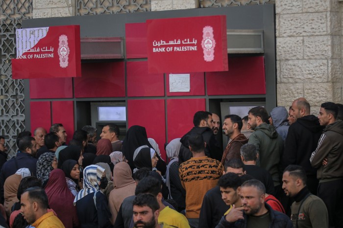 Les employés palestiniens du secteur public se rassemblent autour des distributeurs automatiques de billets 