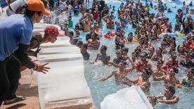 Philippines, Bulacan : des employés poussent des blocs de glace dans une piscine d'un complexe hôtelier