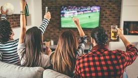 Des amis applaudissent devant la télévision tout en regardant un match de football.