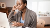 Image symbolique : Femme frustrée assise devant un ordinateur portable.