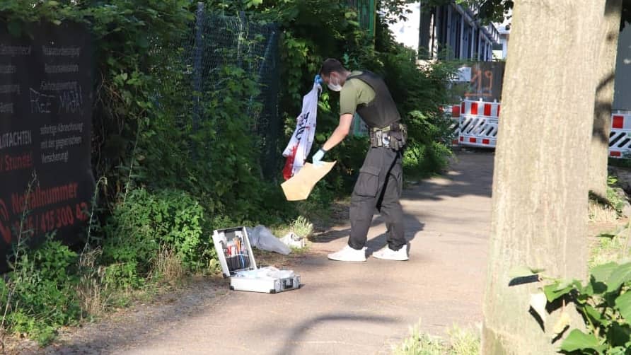 Un policier sécurise un T-shirt taché de sang et le met dans un sac en papier