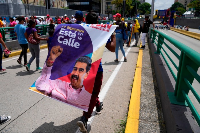 Un partisan de Maduro porte une banderole à son effigie lors d'un rassemblement à Caracas le 4 juillet 2024