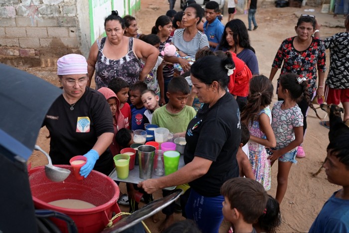 Les gens reçoivent de la nourriture de Carolina Leal, directrice et fondatrice de la fondation Alimentando Sueños, à Maracaibo, au Venezuela, le 12 juin 2024