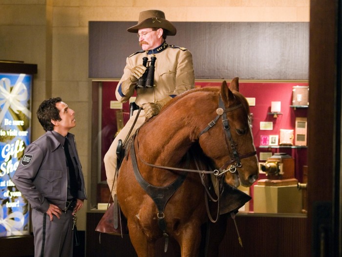 À l'intérieur d'un musée, près d'une exposition d'objets dans une vitrine en verre, un garde regarde un homme en uniforme assis sur un cheval et tenant des jumelles