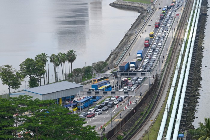 Des automobilistes de l'État malaisien de Johor font la queue au poste de contrôle pour entrer à Singapour