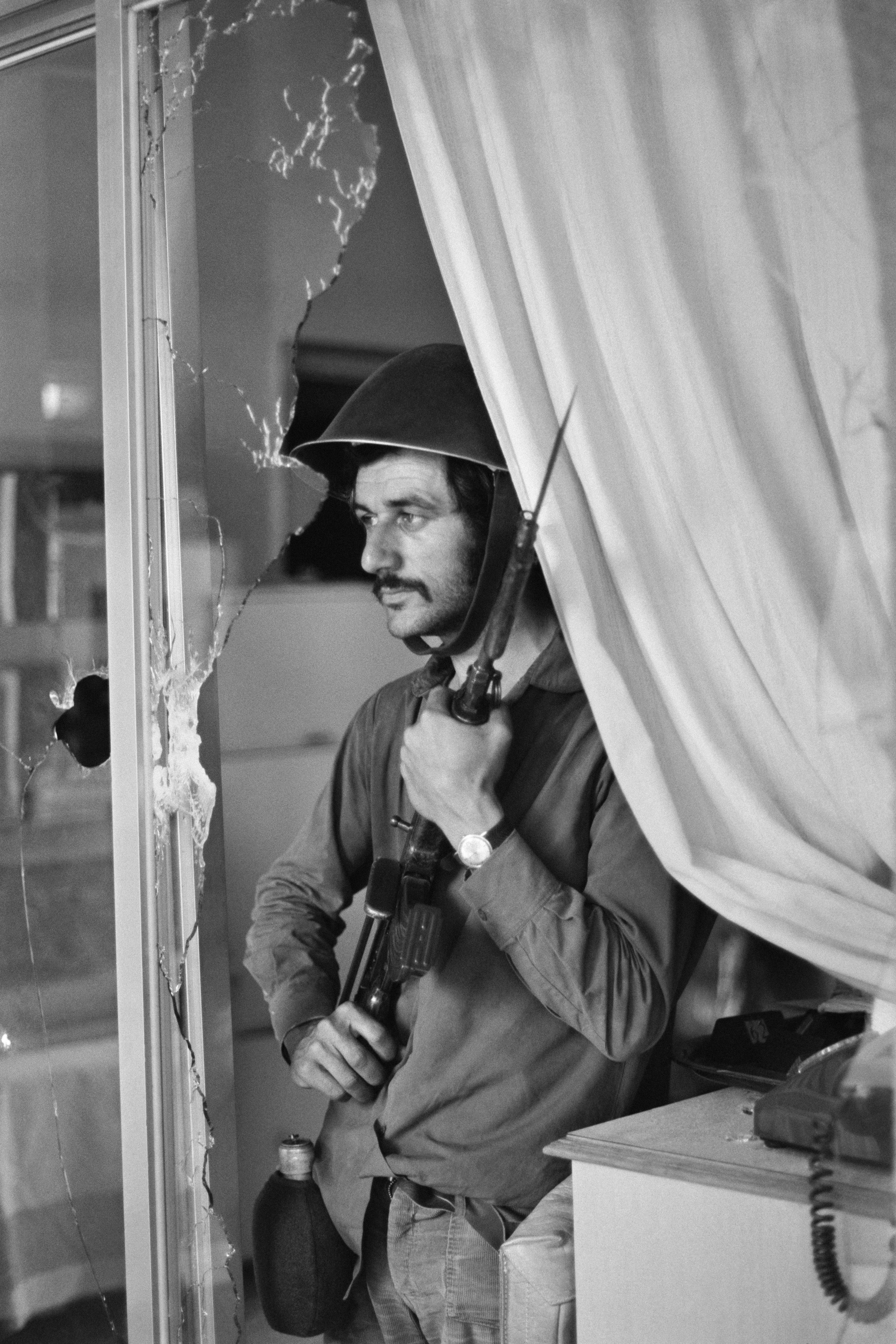 Un bénévole se tient derrière une fenêtre brisée en 1974 à l'hôtel Ledra Palace