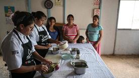 Deux chefs du Ccori Project cuisinent devant trois femmes.