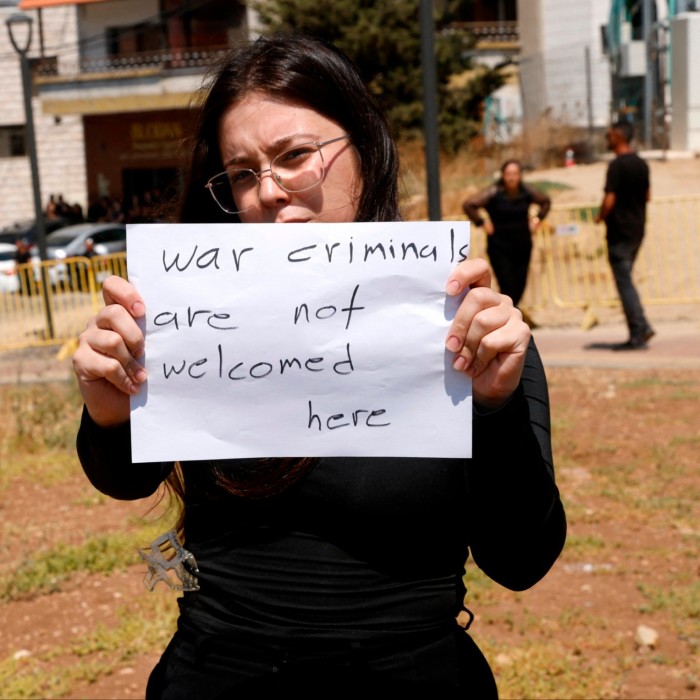 Une femme tient une affiche alors qu'elle et d'autres manifestent contre le Premier ministre israélien lors de sa visite dans le village druze de Majdal Shams