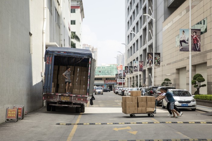 Des ouvriers poussent un chariot de chaussures emballées dans des cartons vers un camion à l'usine Anta de Jinjiang, Fujian