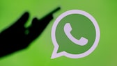 Main tenant le smartphone devant l'arrière-plan du logo WhatsApp
