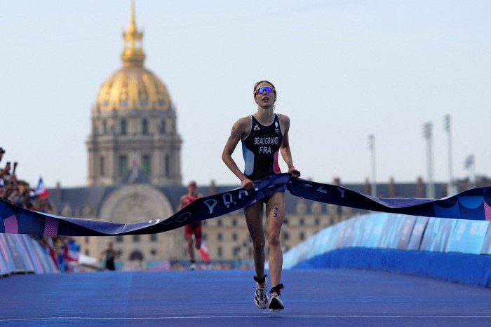 La Française Cassandre Beaugrand franchit la ligne d'arrivée pour remporter la médaille d'or du triathlon individuel féminin aux Jeux olympiques de Paris le 31 juillet 2024