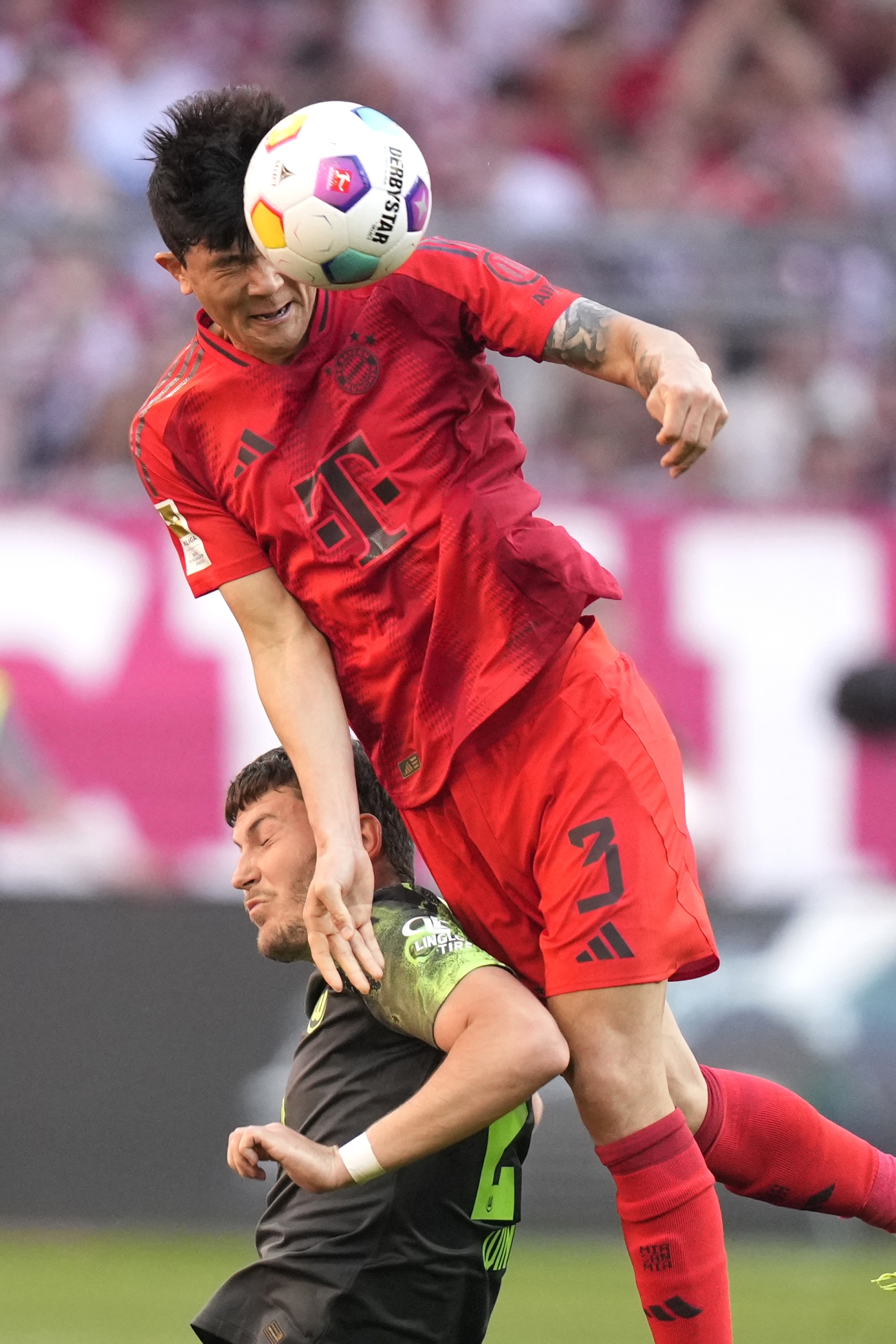 Kim Min-jae du Bayern mène le ballon devant Jonas Wind de Wolfsburg, en bas, lors du match de football de Bundesliga allemande entre le Bayern Munich et le VfL Wolfsburg à l'Allianz Arena de Munich, en Allemagne, le dimanche 12 mai 2024. (AP Photo/Matthias Schrader )