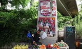 Un vendeur ambulant se tient jeudi à Paris à côté des affiches électorales des candidats du Nouveau Front Popculaire (NFP) de gauche. 