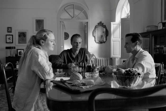 Une image en noir et blanc de deux hommes et d'une femme assis à une table à manger