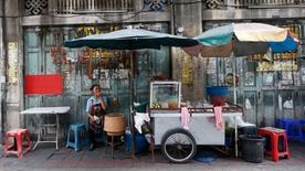 Une femme attend dans un stand de rue à Bangkok
