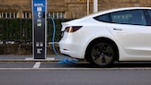 Image symbolique : Voiture électrique blanche en charge sur une borne de recharge.