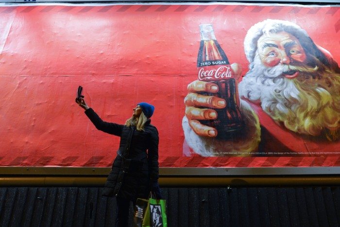 Une femme prend un selfie devant une publicité de Noël de Coca-Cola à Dublin, en Irlande