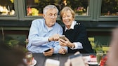 Couple de personnes âgées assis à la table avec un téléphone portable