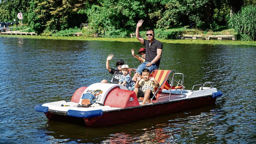 Hang (34 ans, de gauche à droite), Tino (2 ans), Mio (6 ans), Long (38 ans) et Philip (8 ans) de Berlin ont loué un pédalo pour la première fois et se rafraîchissent sur l'eau.