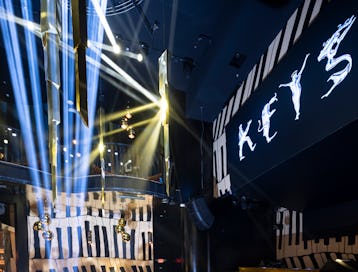 Intérieur d'une discothèque avec éclairage bleu et poutres, comportant un balcon étiqueté "CLÉS" illuminé...