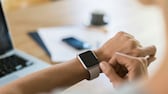 Femme au bureau regardant une montre intelligente