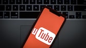 Le logo YouTube sur l'écran d'un smartphone devant le clavier d'un ordinateur portable