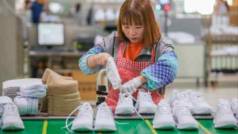 Une femme emballe une paire de chaussures dans une usine de la ville de Jinjiang, dans la province du Fujian, au sud-est de la Chine