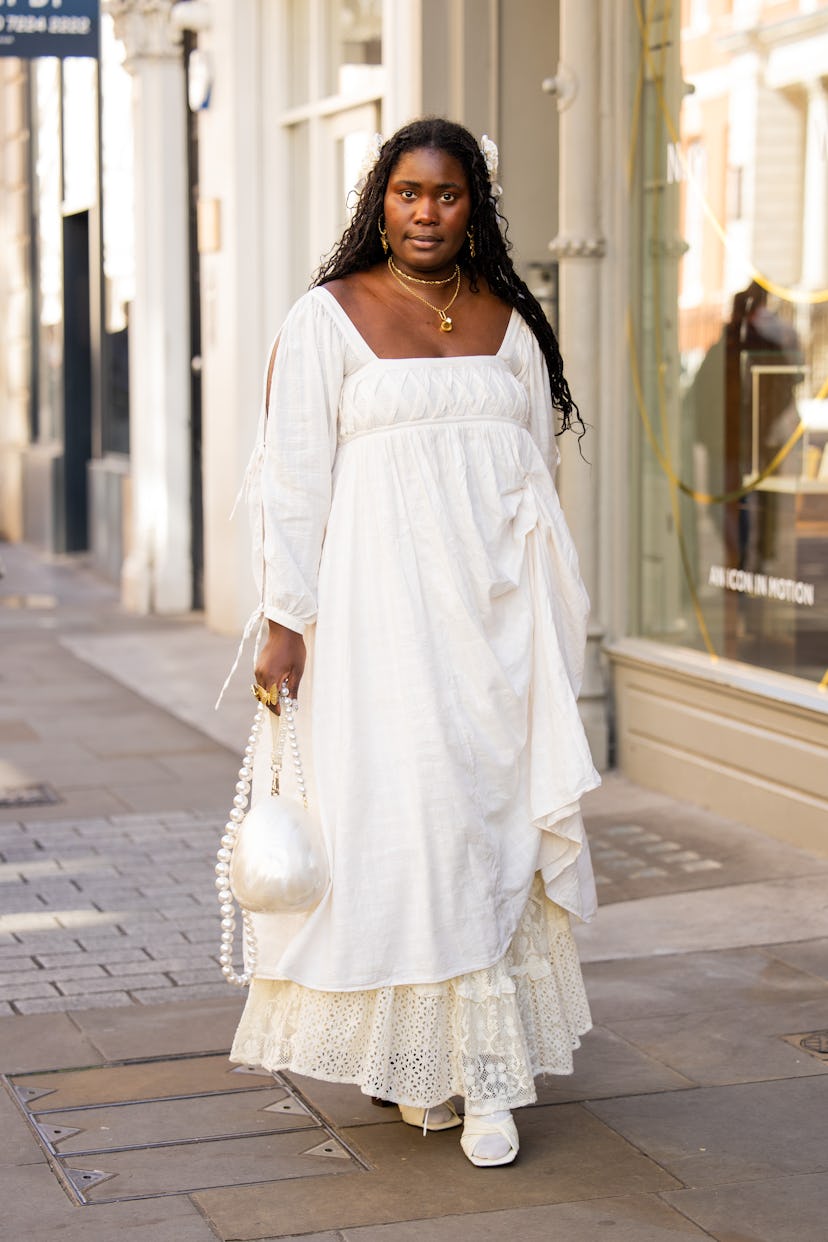 Une invitée porte une robe blanche, une jupe à lacets et un sac rond à l'extérieur de Bora Aksu pendant la Fashion Week de Londres 